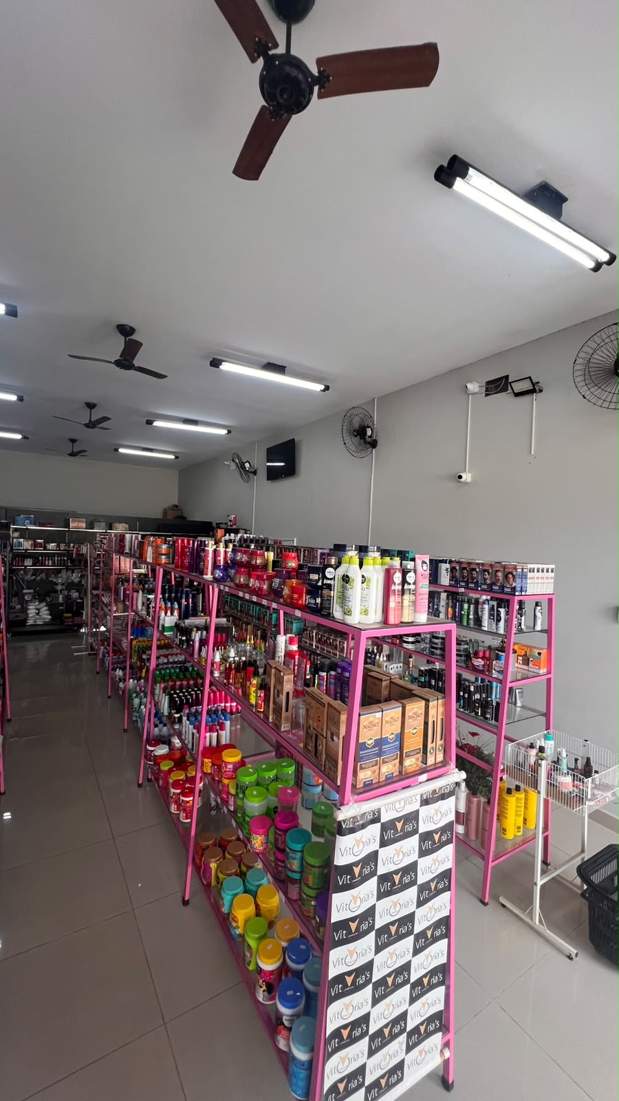 Interior da loja com corredores de prateleiras rosa cheias de produtos organizados por categoria